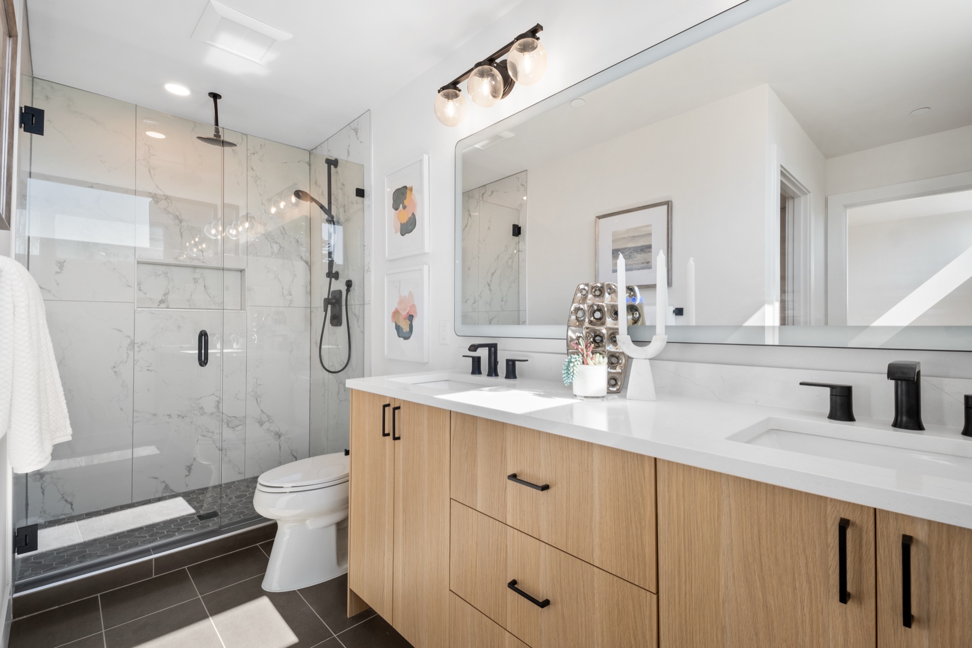 Modern bathroom with black fixtures, wood vanity, and glass shower
