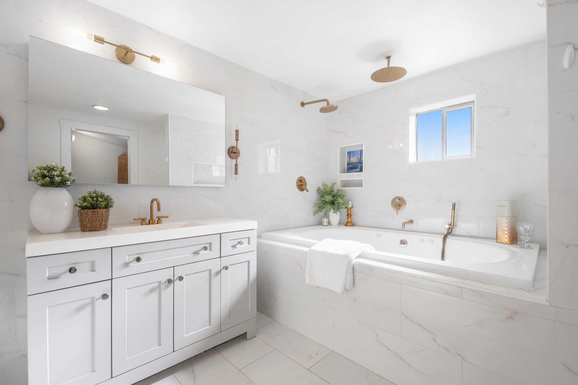 Marble primary bathroom with soaking tub and gold fixtures