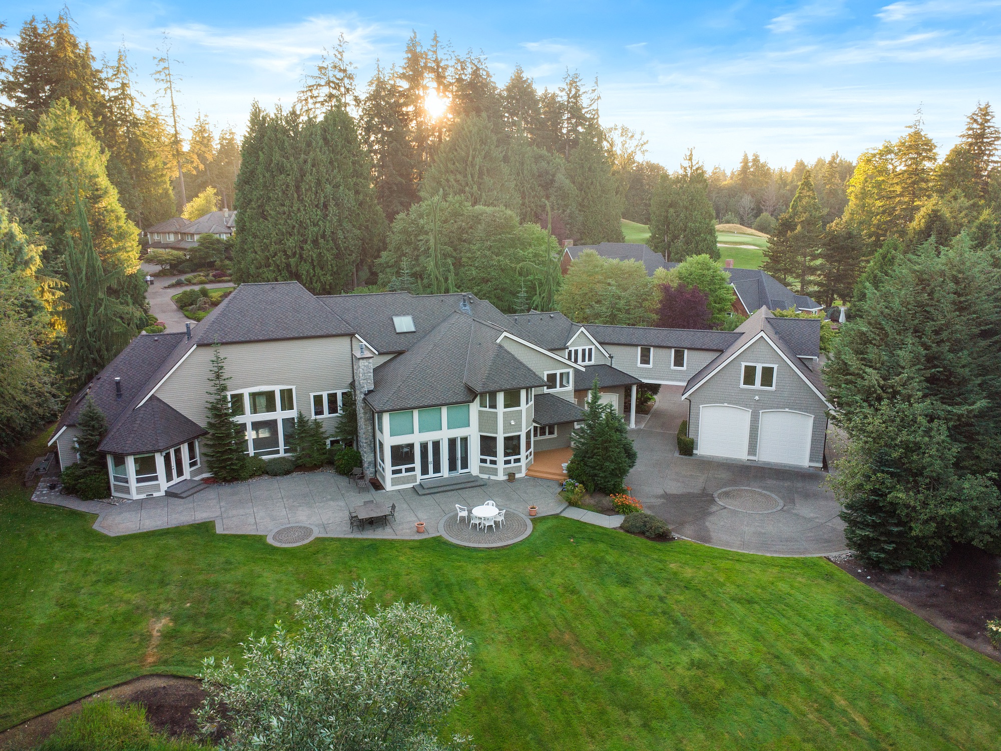Aerial view of a large estate home with circular driveway bordering a golf course
