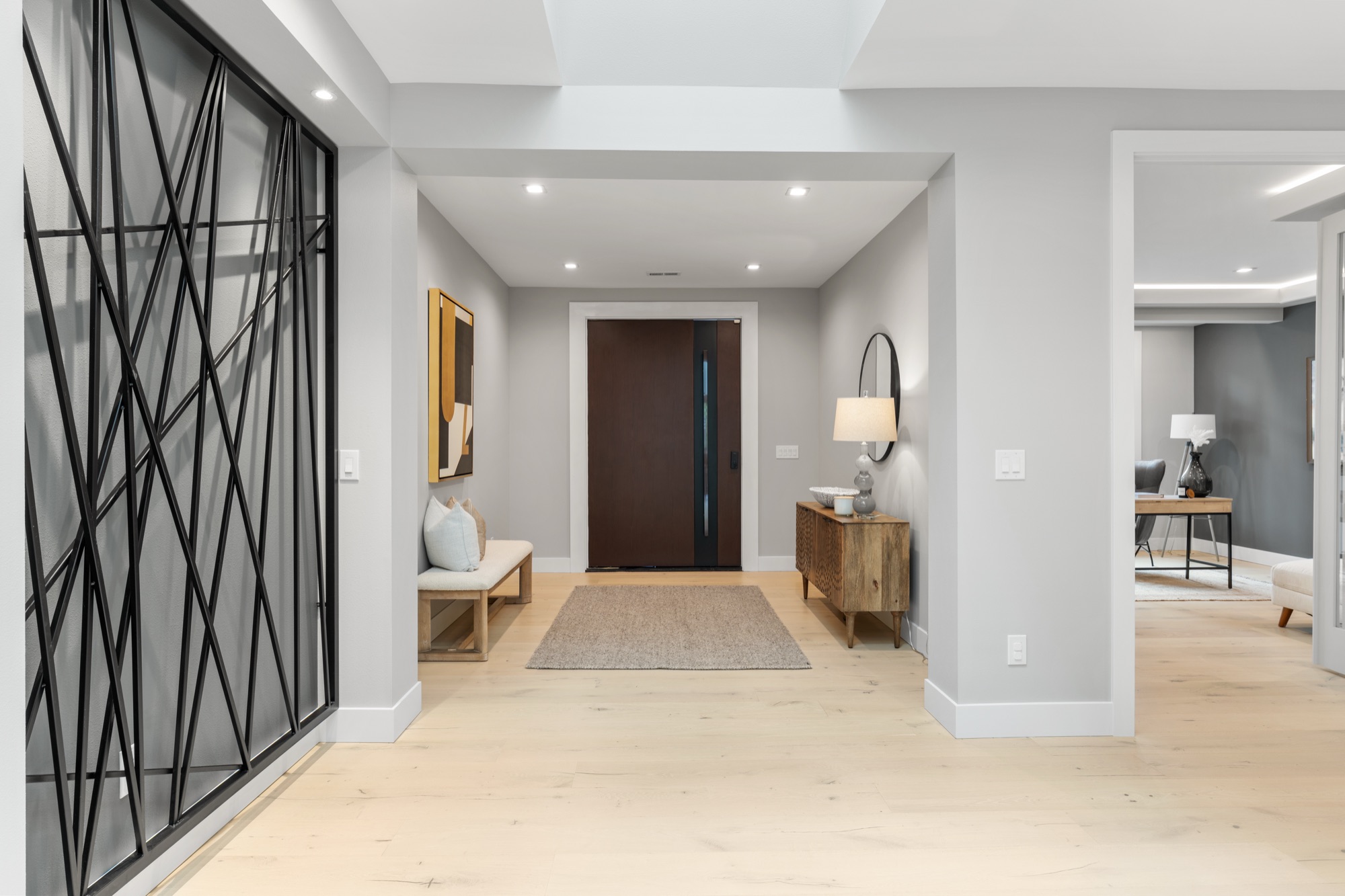 Modern entry foyer with black metal accent panel and wood console