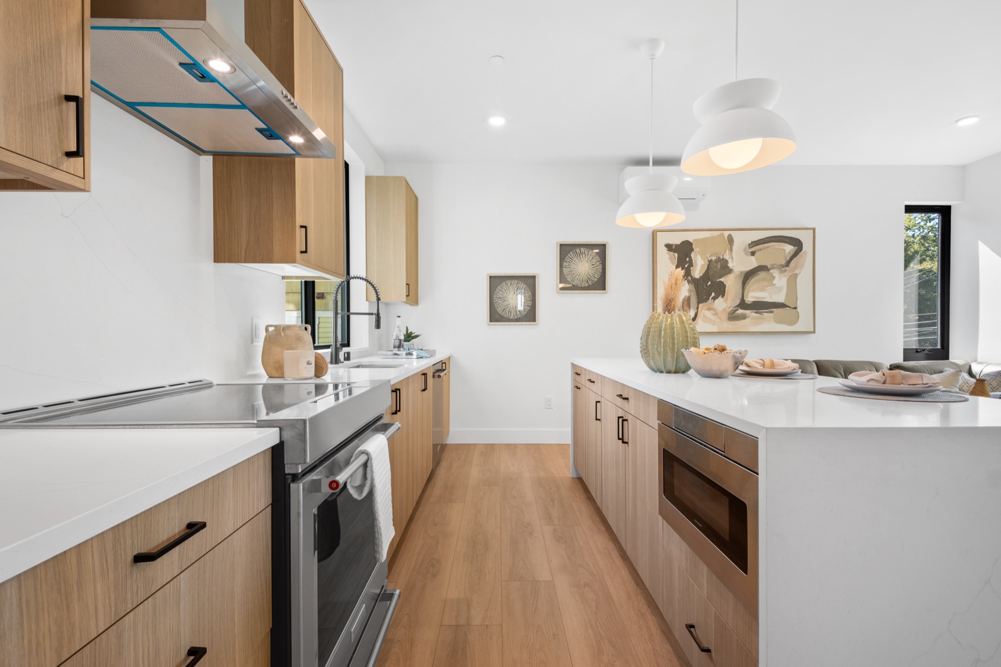 Light wood modern kitchen with white countertops and pendant lighting